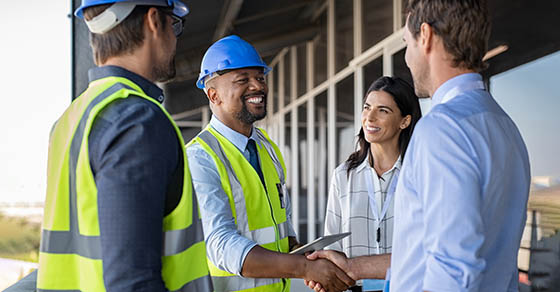 Construction contractor reviewing paperwork with a business advisor, discussing private equity investment options and shaking hands